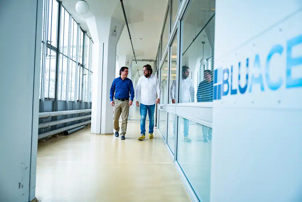 Een foto van medewerkers van Bluace voor het kantoor in de Van Nelle Fabriek