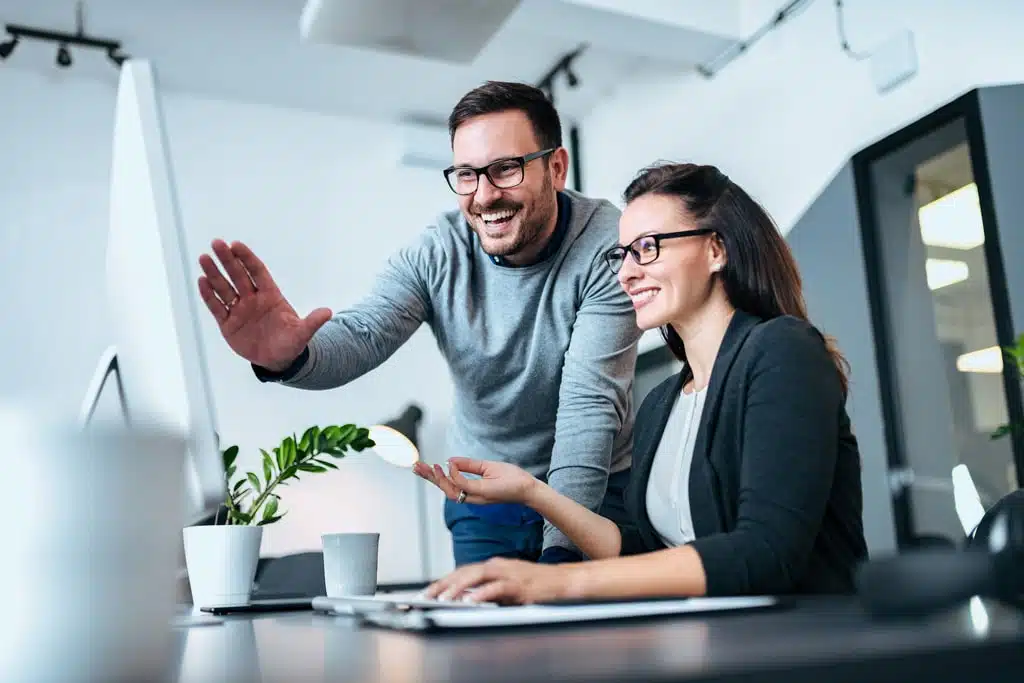 Twee medewerkers achter de computer die met elkaar overleggen