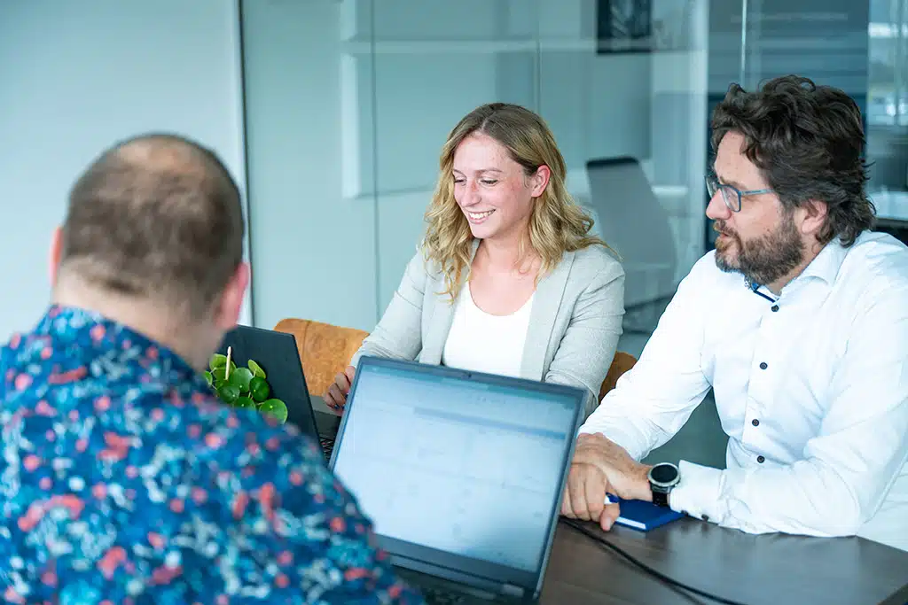 Een foto van medewerkers van Bluace in de vergaderzaal achter hun computer